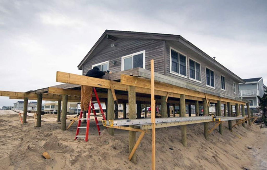 Image of a home being raised onto stilts to protect it from storm surge and flooding